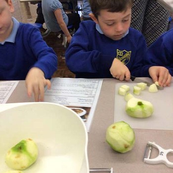 Plentyn yn torri afalau mewn ciwbiau