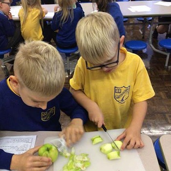 Plant yn torri ac yn pilio afalau ar y bwrdd