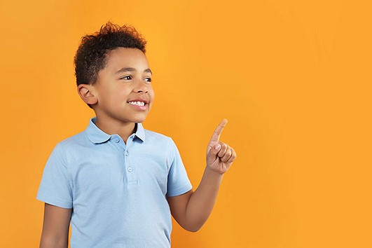 A young boy in a blue polo shirt pointing